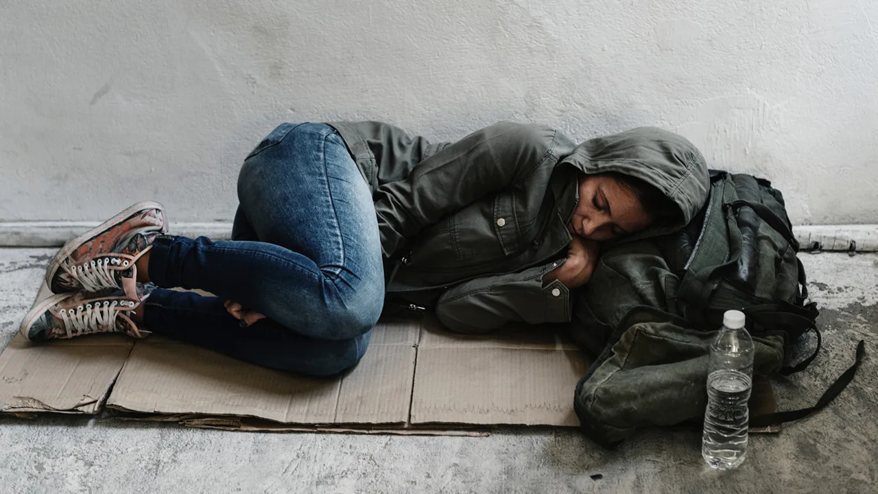 A homeless woman sleeping on cardboard outside