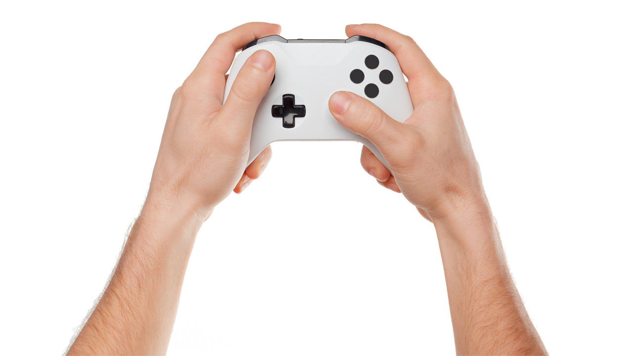 A male hand holding a video game controller