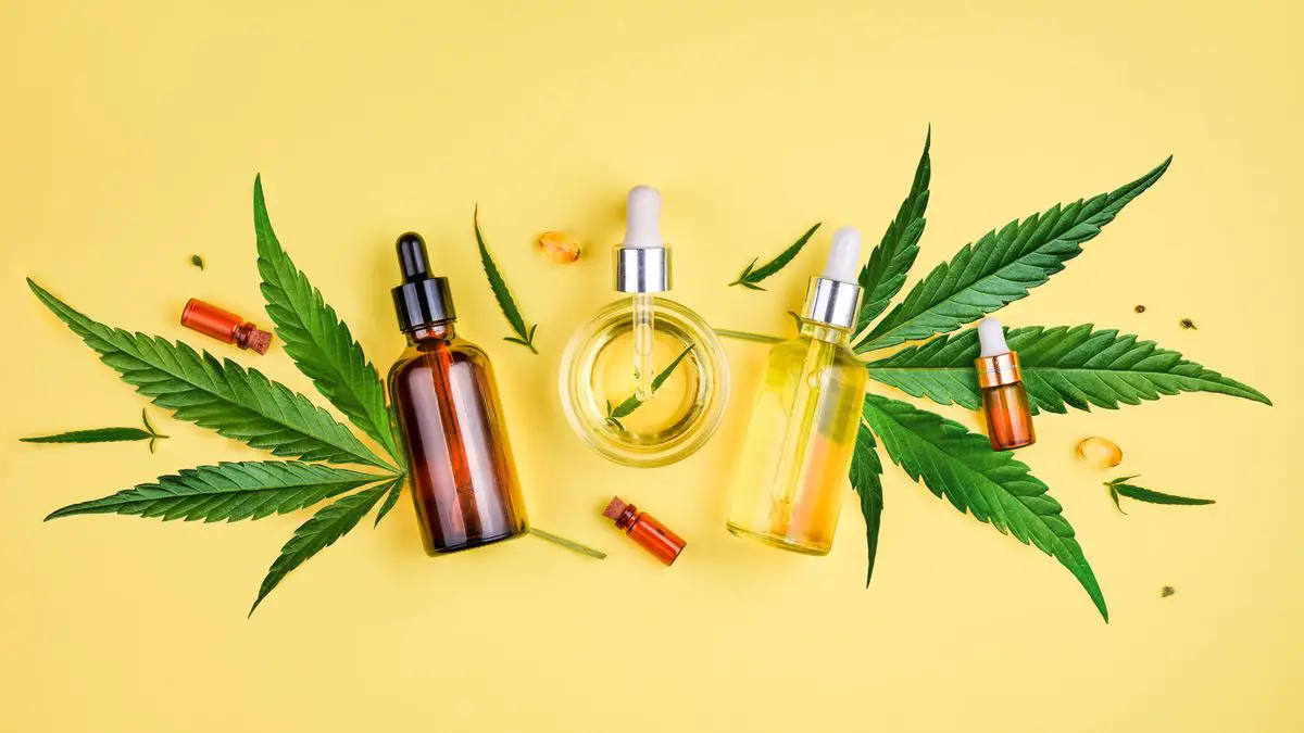 Different glass bottles with CBD OIL THC tincture and cannabis leaves