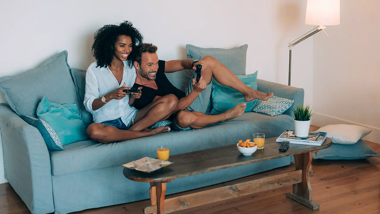 Happy young couple relaxed at home in the couch having fun playing video games