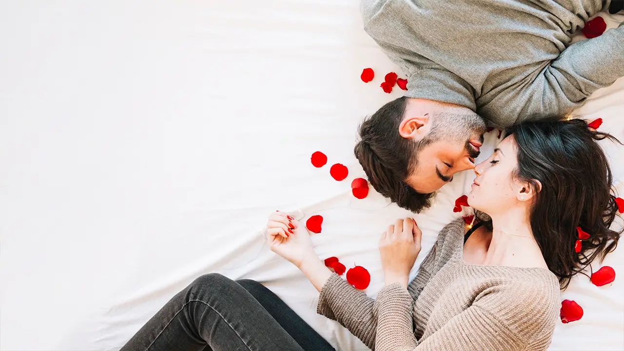 Couple sleeping on a white bed with noses touching