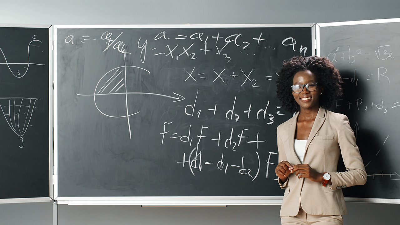 A Mathematician standing behind a writing board with math problems written on it