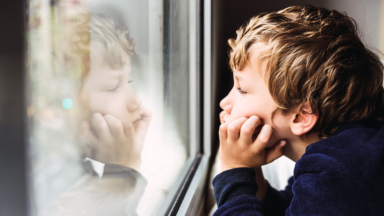 a bored kid looking out the window of his room