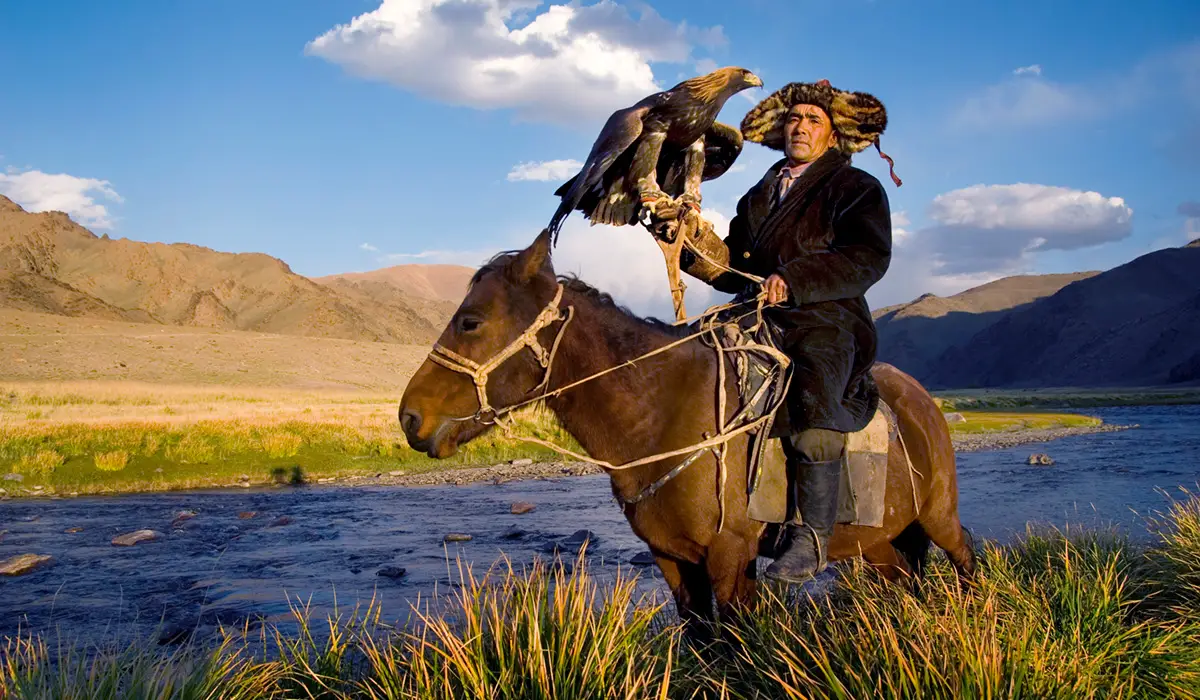 A man riding a horse with an eagle on his hand