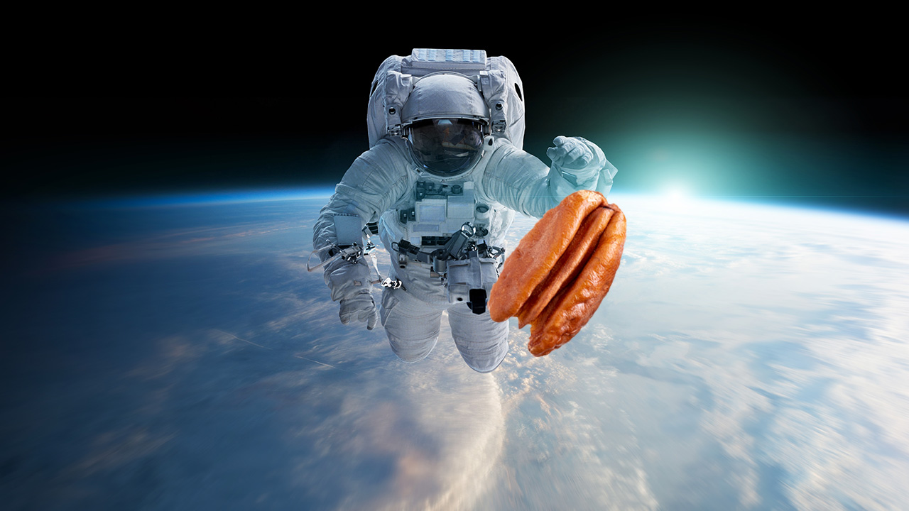 an astronaut in space reaching out for a pecan