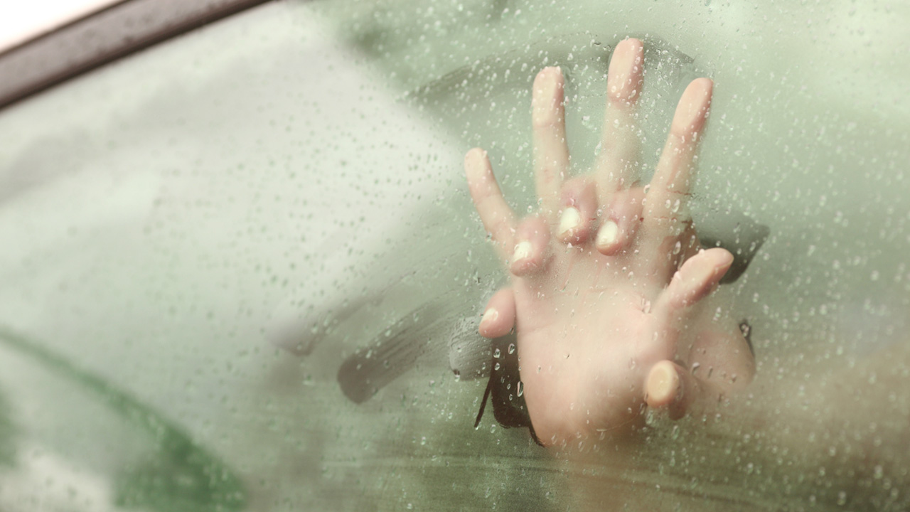 Two hands pressed in a steamy car window