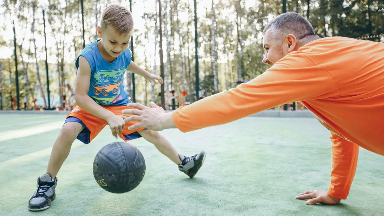 Father and son playing basketball outside