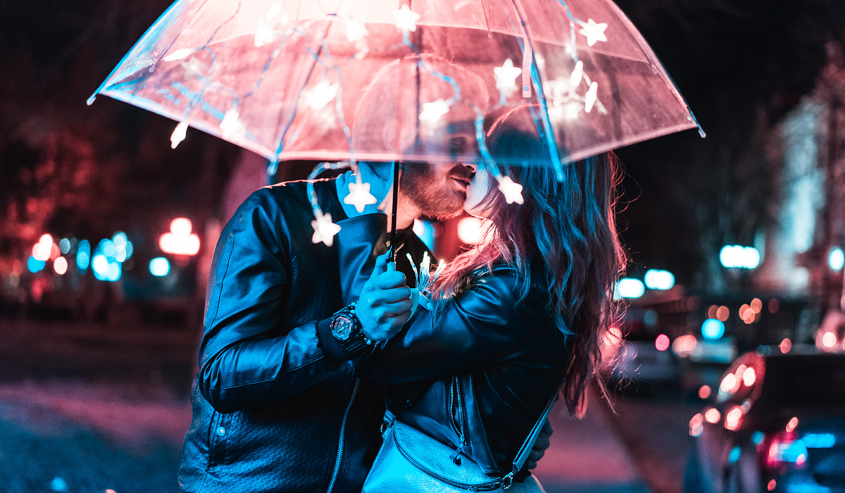 Guy and girl kissing under an umbrella