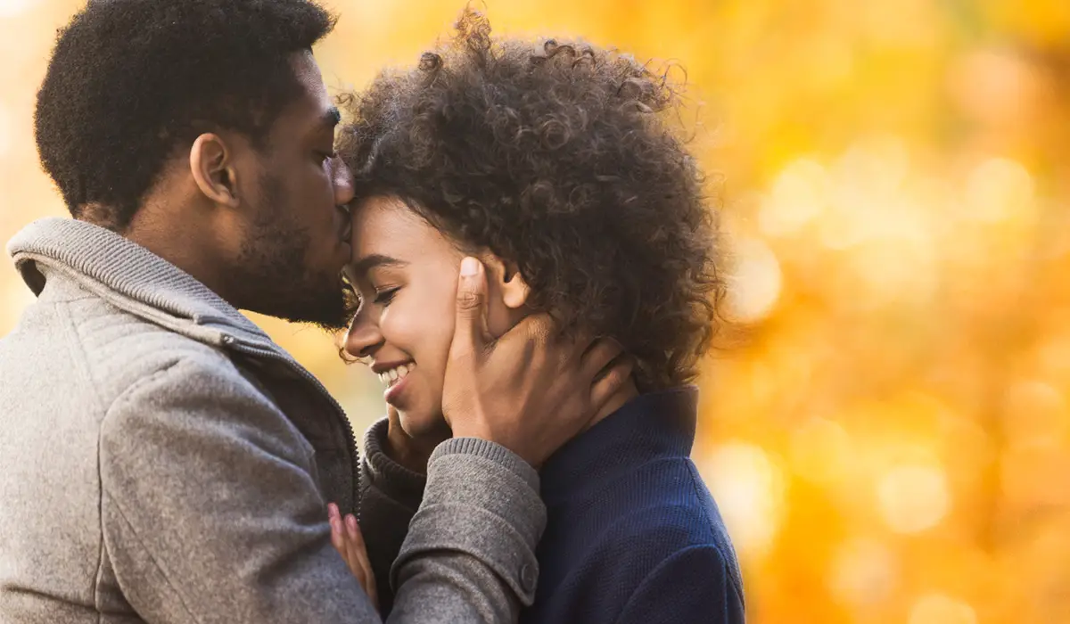 Man kissing a woman on her forehead