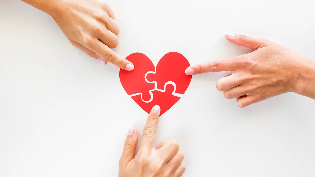 Top view of hands touching puzzle heart pieces
