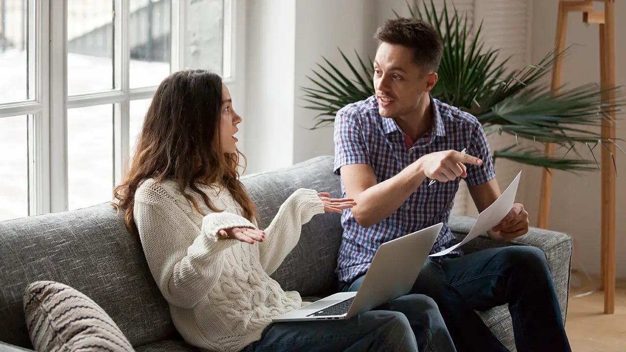 Couple arguing about high bills with laptop documents