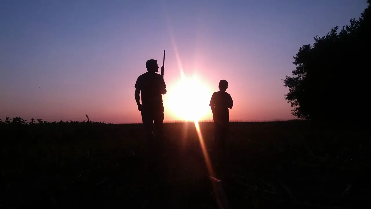Silhouette of father son hunting sunset