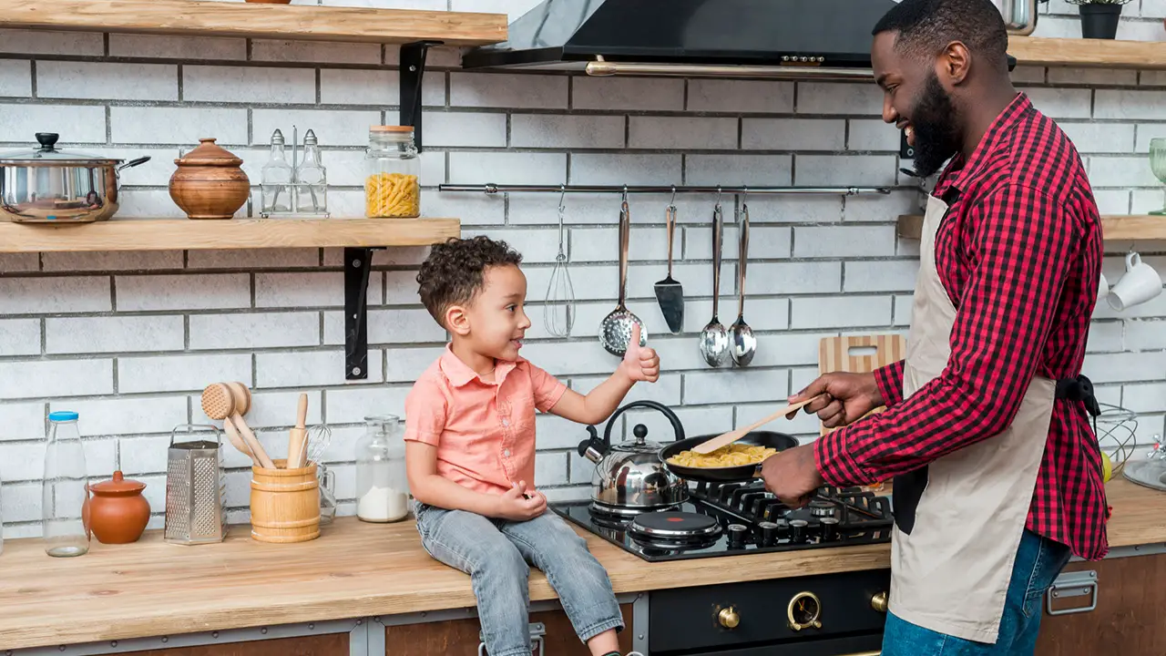 Son giving thumbs up to dad while cooking together