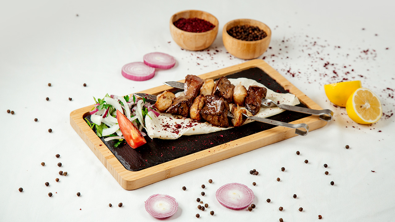 Liver kebab with fat and onions on a wooden board
