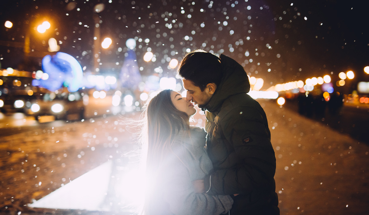 Woman and man kissing while its snowing